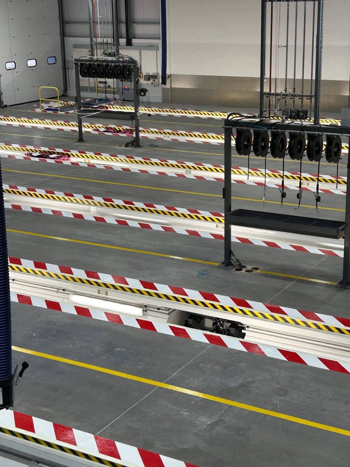 Industrial workshop floor line marking installation in Motherwell, Scotland showing yellow traffic guidance lines and inspection pit hazard chevrons on concrete floor